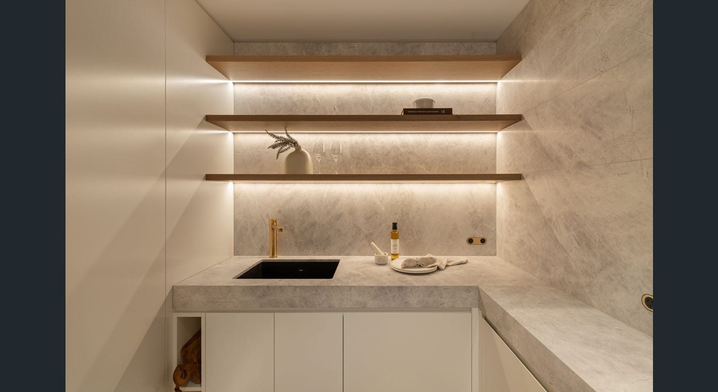 Butler's pantry with stone benchtops and lit timber shelving